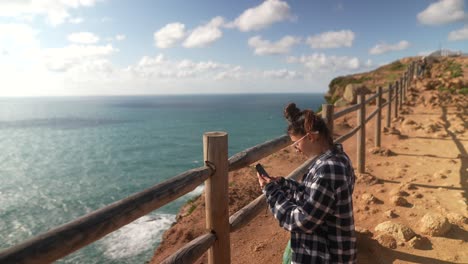 mujer tomando una foto en el punto de vista del océano