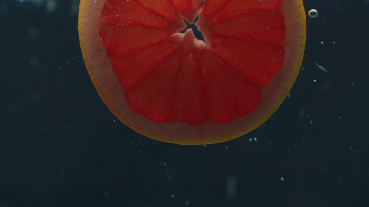 anillos de pomelo bajo el agua con burbujas de aire y en cámara lenta. fresco y jugoso vegetariano saludable.