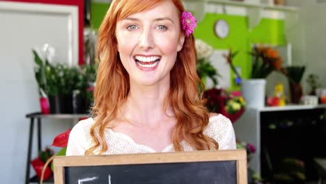 Smiling-florist-holding-flower-shop-sign-on-slate