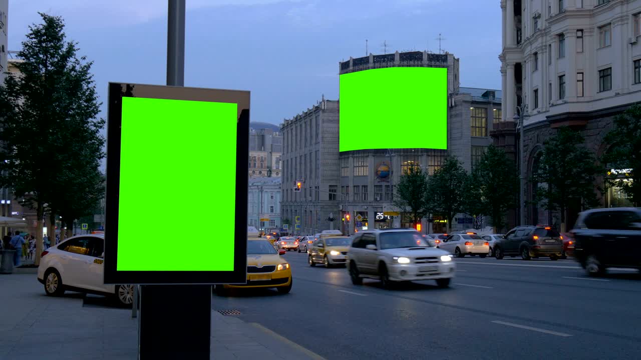 To billboards med en grøn skærm. Om aftenen, på en travl gade