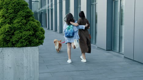 Two women walking their dog in a city setting