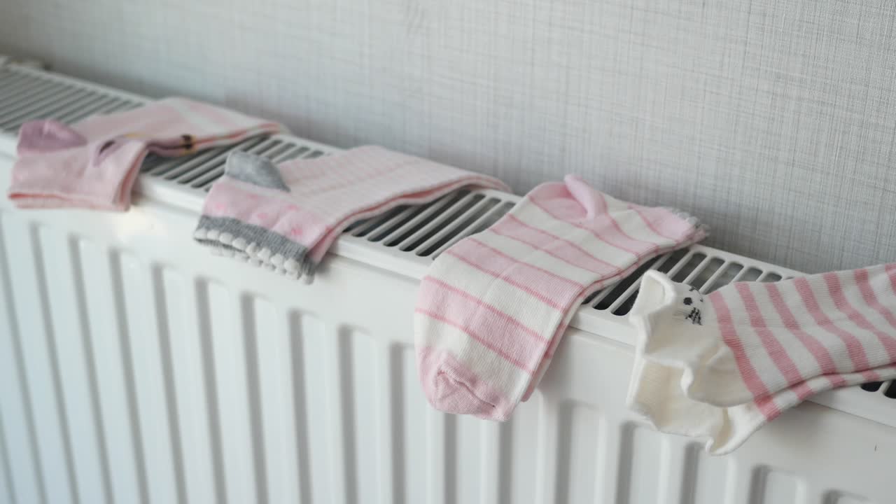 Pink Striped Children's Socks Drying on a Radiator