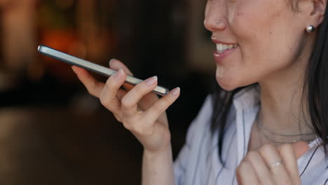 mujer usando reconocimiento de voz en un teléfono inteligente en un café