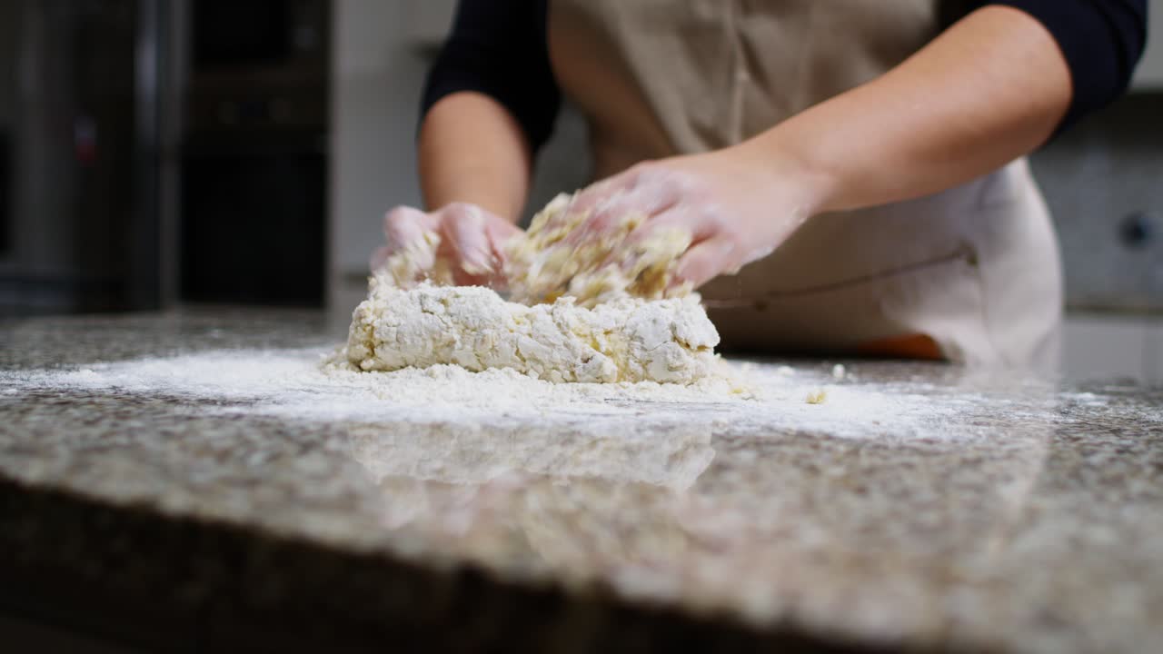 Close-up of hands kneading dough with flour on a kitchen countertop.