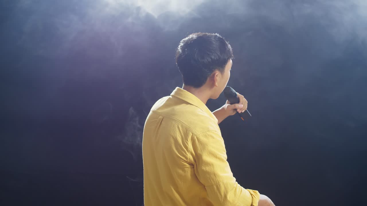 백색 연기 검은 배경에 마이크를 들고 하는 어린 소년의 뒷면