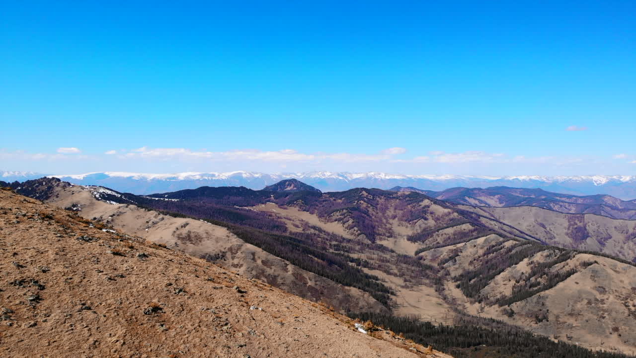 Vast Mountain Landscape with Distant Snow-Capped Peaks under a Clear Blue Sky