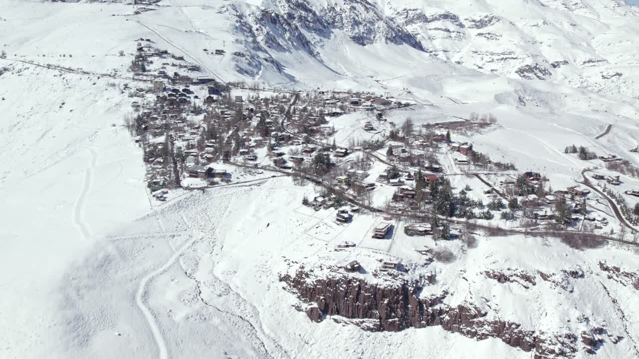 estableciendo una vista aérea sobre el bosque de pinos de montaña de invierno de farellones y las casas del vecindario cubiertas de nieve