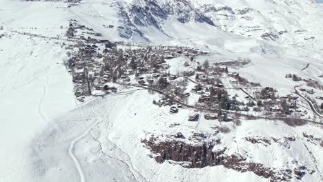 Establecer-Una-Vista-Aérea-Sobre-Los-Farellones,-El-Bosque-De-Pinos-De-Montaña-Invernal-Y-Las-Casas-De-Barrio-Cubiertas-De-Nieve.