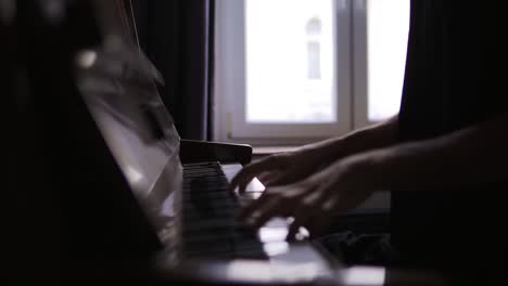 close-up of male's hands practicing to play the piano at home