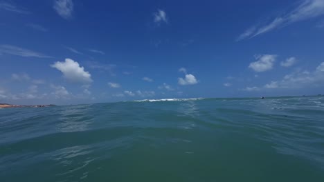 Handheld-shot-of-small-waves-passing-under-the-camera-from-the-tropical-Madeiro-beach-in-Pipa,-Brazil-in-the-state-of-Rio-Grande-do-Norte-with-warm-clear-turquoise-water