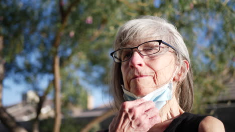 paciente caucásica de mediana edad que respira aire fresco al aire libre y luego se pone la máscara del hospital para prevenir enfermedades contagiosas