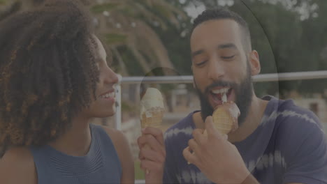 eating ice cream cones, couple sitting outdoors on sunny day, sharing smiles