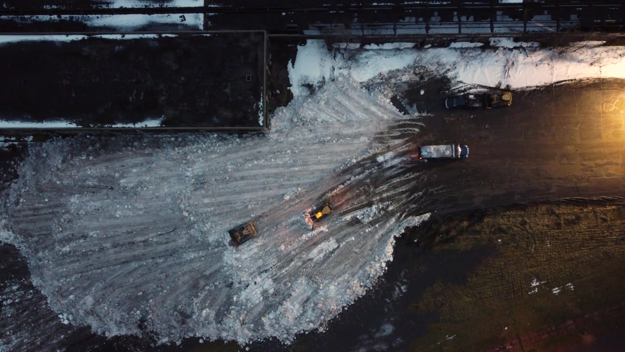 Escavatori minerari industriali scaricano dumper pieni di neve. Vista dall'alto con drone