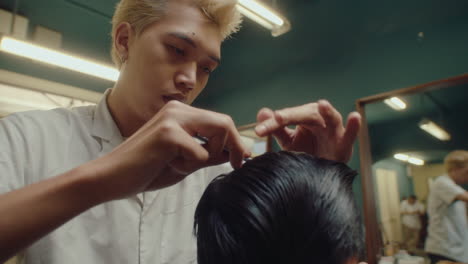 asian barber combing and parting hair of client