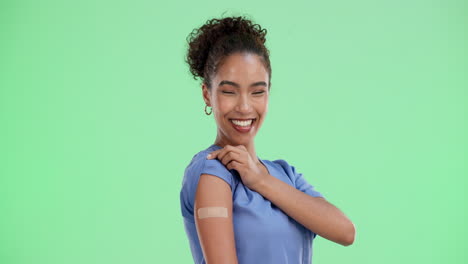 a happy nurse with a band-aid on her arm after receiving a vaccine