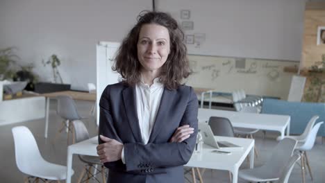 businesswoman standing with crossed arms and smiling at camera