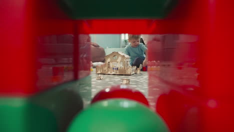 boy builds wall from colorful blocks sitting near house