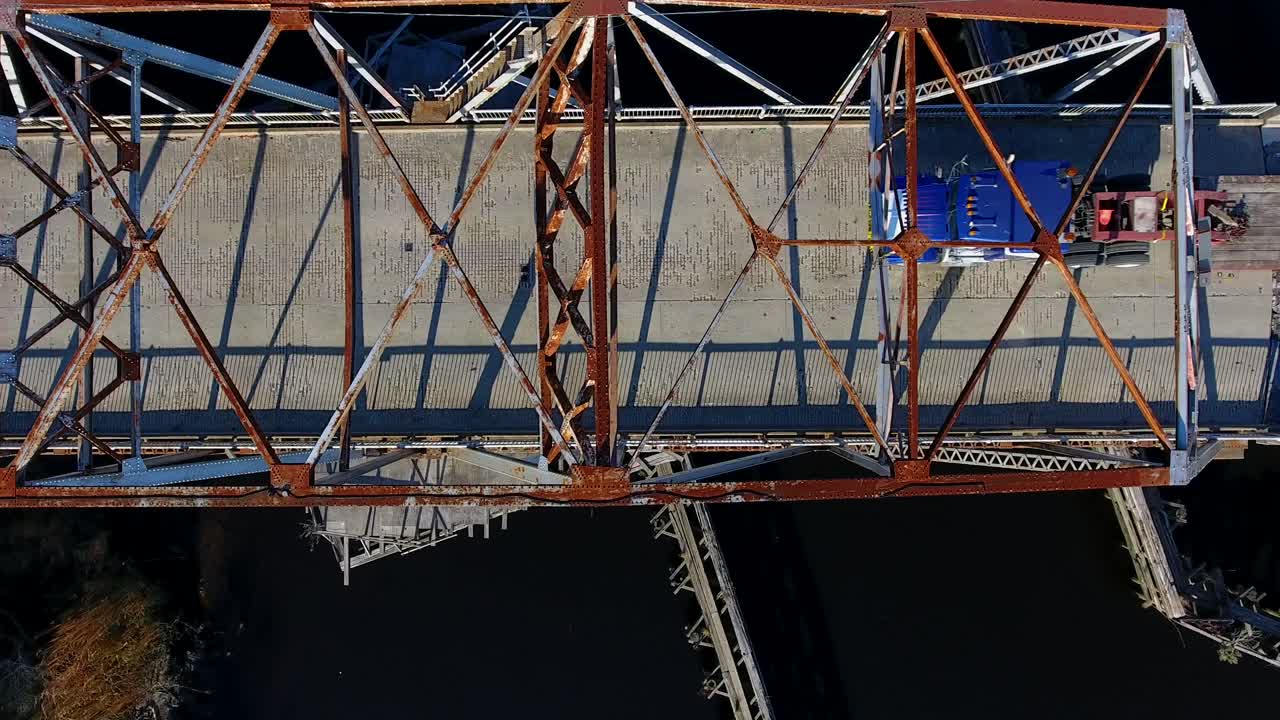 Birds-eye-view of an old bridge, a semi-truck passes by.