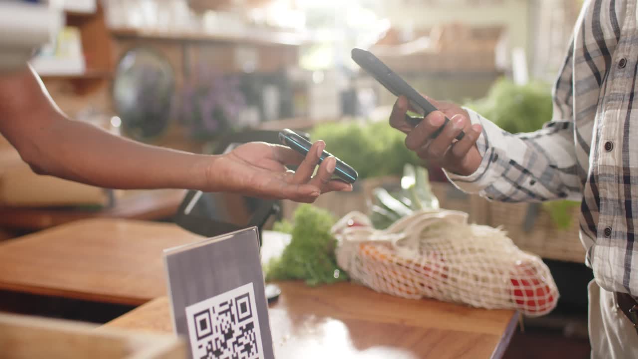 Midsection of senior african american man paying using smartphone at health food shop, slow motion