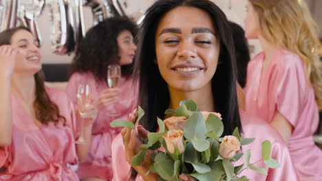 Mujer-Sosteniendo-Un-Ramo,-Vestida-Con-Un-Camisón-De-Seda-Rosa,-Sonriendo-Y-Mirando-A-La-Cámara