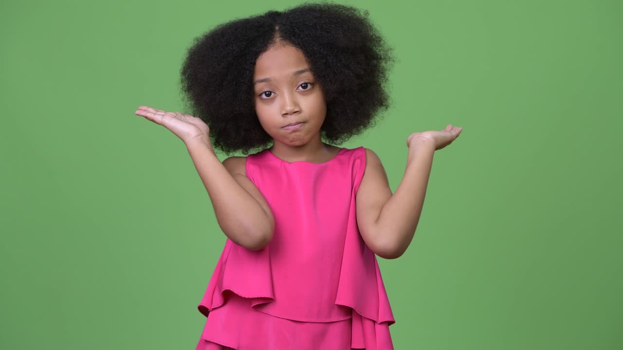 Young cute African girl with Afro hair shrugging shoulders