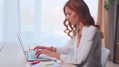 young redhead caucasian woman journalist typing article on laptop keyboard