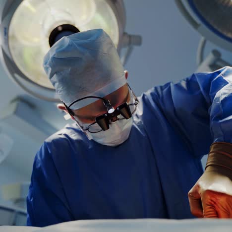 portrait of a doctor in mask under surgical lamp. professional surgeon performing an operation with medical instruments in the operating room