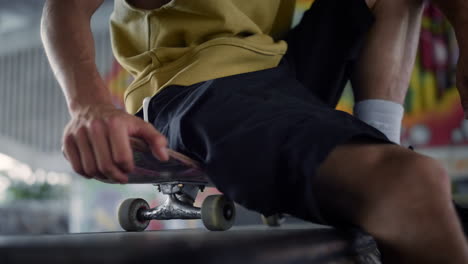 Unrecognizable-man-relaxing-skatepark.-Skater-resting-after-training-outdoors.