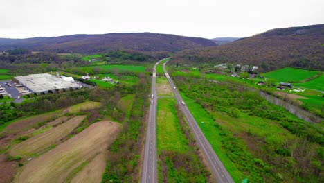 Aerial-showing-semi-trucks-navigating-through-Milesburg-PA-on-I-80-interstate,-vital-for-logistics-and-transport