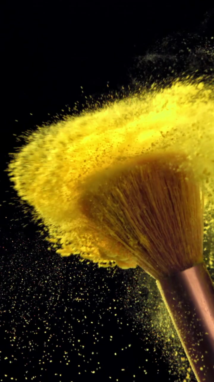 Brochas de Maquillaje Golpeando y Soltando Polvo Amarillo a Cámara Lenta