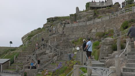 people navigating terraced stone steps and gardens on a hillside