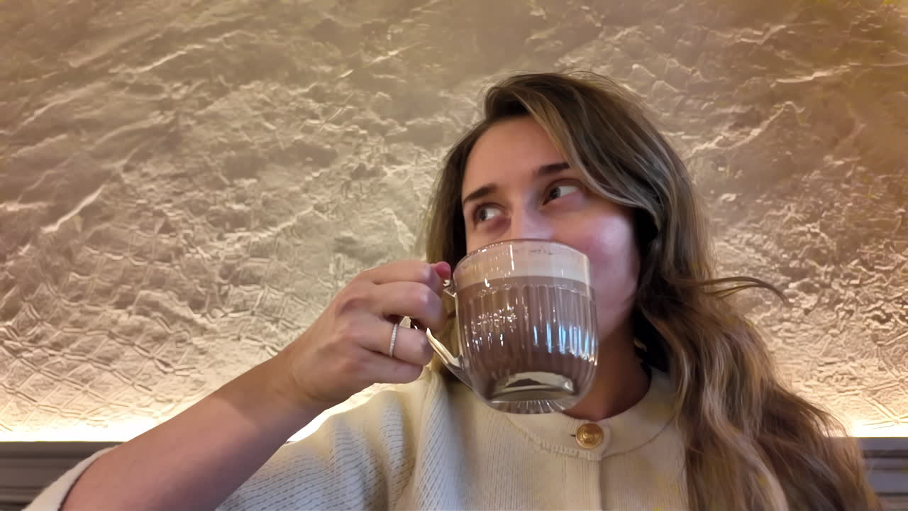 Brunette, young woman drinking coffee with a biscuit at a cafe