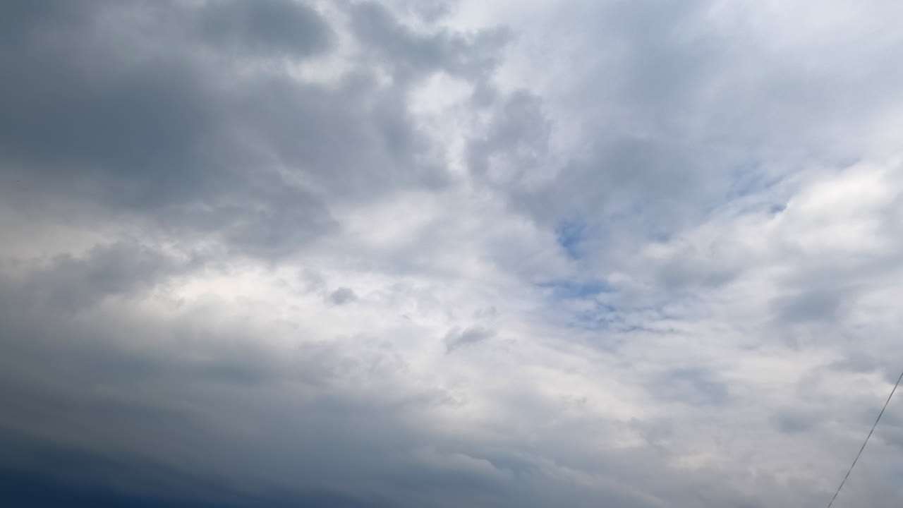 Huge grey clouds gather in atmosphere. Low angle view on the dramatic rainy cloudscape spreading by the sky. Timelapse.