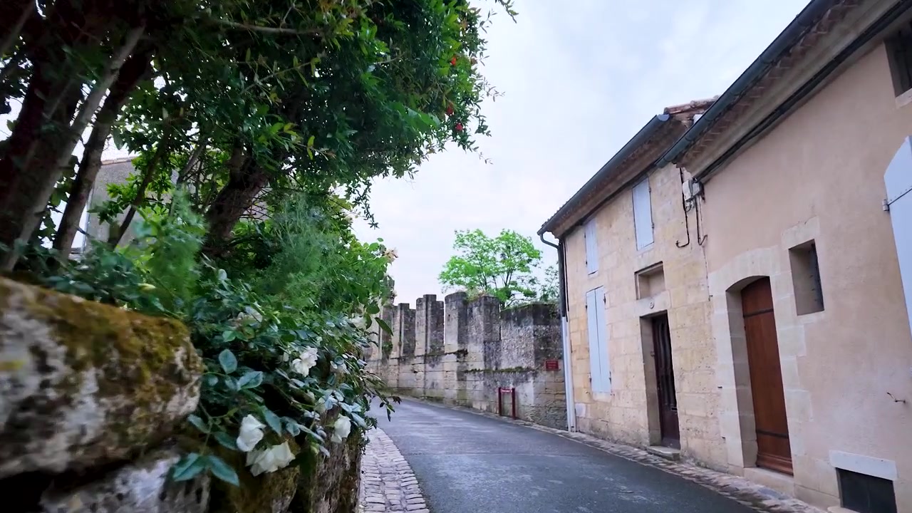 Una lenta carrellata si muove lungo una tranquilla strada di paese con architettura storica in pietra.