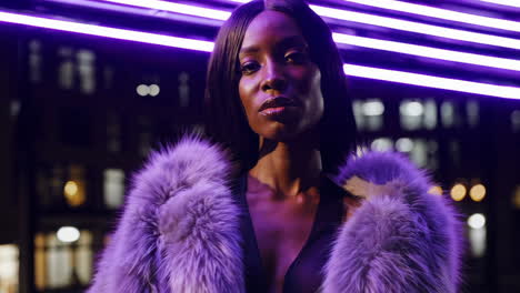 stylish woman in faux fur coat under purple neon lights