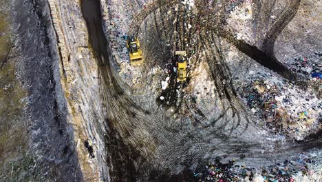 aerial flyover landfill full of trash, pollution environmental problem, garbage, trucks dump waste products polluting in a dump, wide angle revealing drone shot moving backward camera tilt up