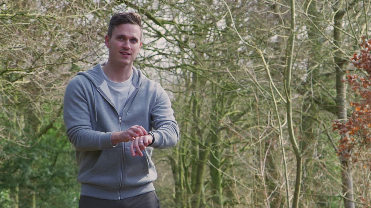 мужчина бежит в деревне, занимается спортом, проверяет смарт-часовки, фитнес-приложение.