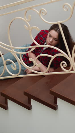 sorrowful woman lies on steps in residential house. frustrated lady with stress and trauma symptoms rests on stairs. mental health and psychology