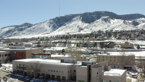 an aerial shot moving backwards revealing a small tower in the middle of a small town overlooking snowy mountains in the winter