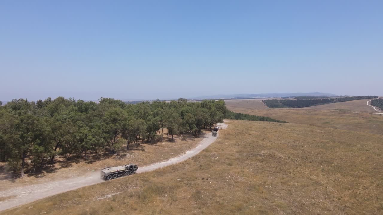 soldados del escuadrón del ejército de israel en vehículos que conducen a través del campo verde en la carretera rural del campo de entrenamiento, tiro de seguimiento aéreo