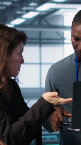vertical video developers in data center workspace coding on laptop, analyzing metrics