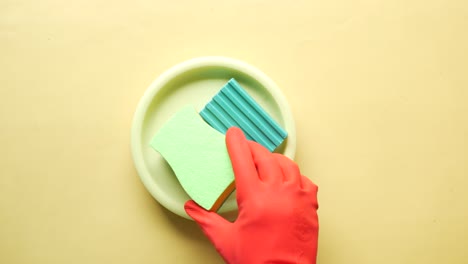 sponge , rubber gloves and ful plate on pink