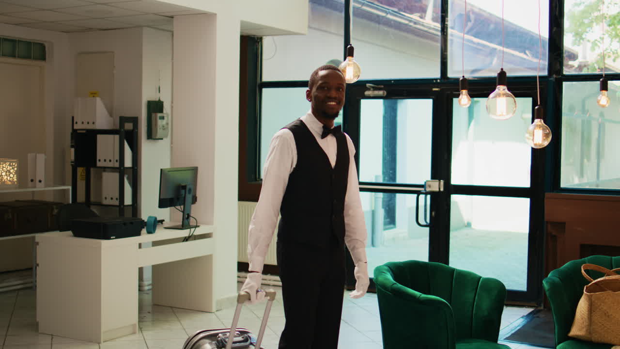 Hotel bellhop carrying lugagge in lobby
