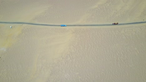 atacama desert with a road and two trucks passing from an aerial top down view in peru, south america