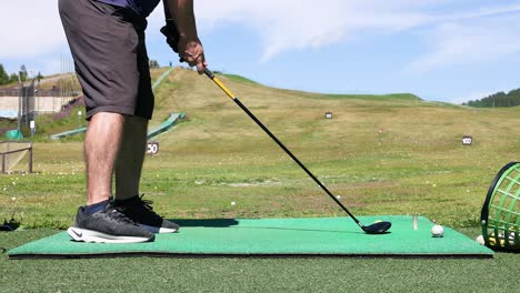 man practicing golf swing on green field