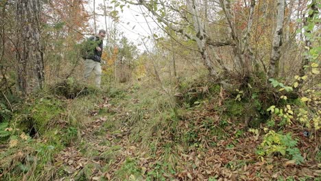 A-person-walking-towards-the-camera-through-the-bushes-with-fall-colours-surrounding-him