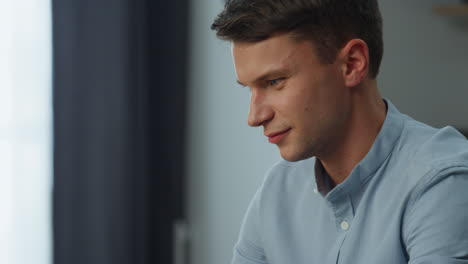 Smiling-man-greeting-colleagues-having-online-conference-at-home-office-closeup