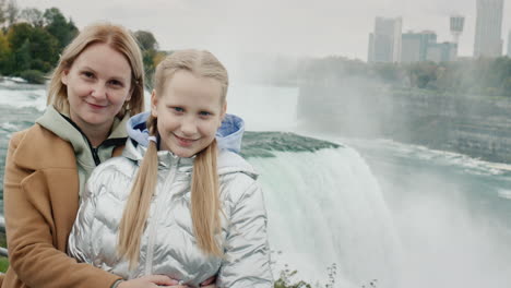 portrait of a mother with a daughter of ten years against the background of the famous niagara falls