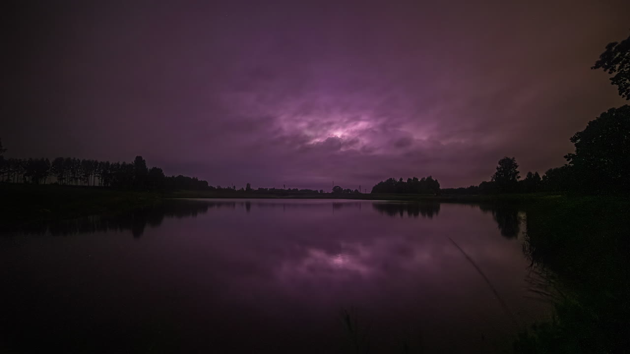 lapso de tiempo de un lago con un cielo estrellado al atardecer que se convierte en uno tormentoso cuando los vehículos pasan por un puente