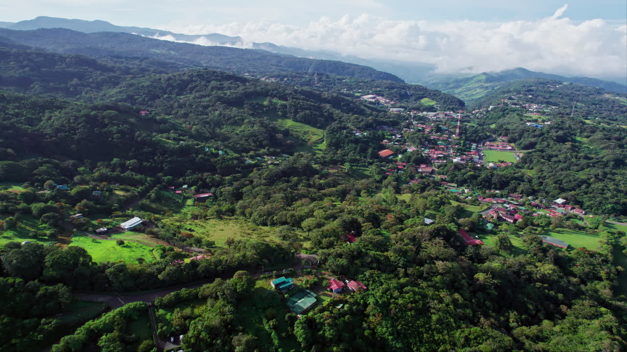 A rising aerial over the mountain town Santa Elena, a popular destination for tourists in the lush mountains of Costa Rica, with hiking trails, and scenic views of fog over the biodiverse tree canopy.